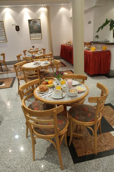 un comedor con mesas y sillas con comida. en Gran Hotel Ailen en Buenos Aires
