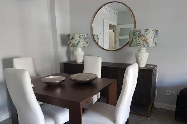 mesa de comedor con sillas blancas y espejo en Precioso apartamento en la Costa del Sol, en Torremolinos