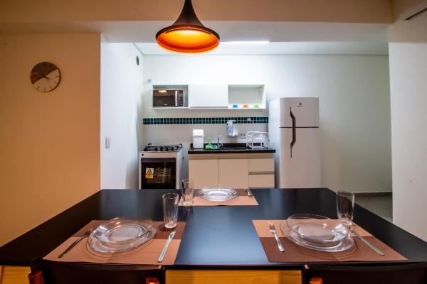 una cocina con una mesa con platos y vasos. en 360 Suítes Santa Ifigênia - Apartamentos mobiliados, en São Paulo