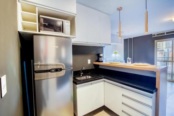 cocina con armarios blancos y refrigerador de acero inoxidable en 360 Suítes Vibe República - Apartamentos mobiliados, en São Paulo