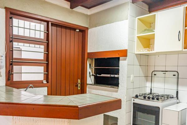 a kitchen with white cabinets and a stove top oven at Casa Geminada duplex 04, Jurerê a 3 quadras da praia JUR184 in Florianópolis