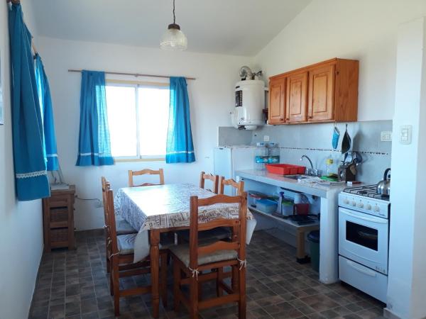 cocina con mesa y sillas y cocina con cortinas azules en Alas Mágicas, en Villa Yacanto