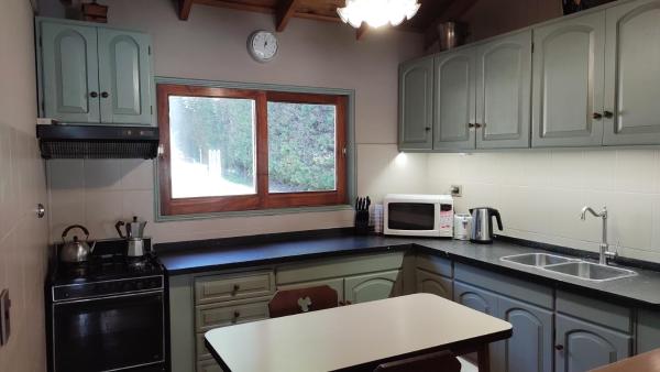 cocina con armarios verdes, fregadero y ventana en Casa CAVOK en San Carlos de Bariloche
