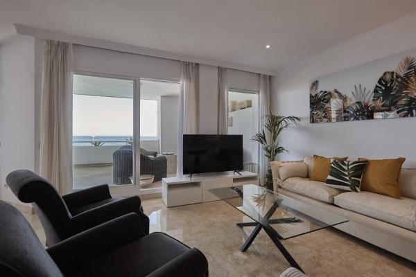sala de estar con sofá y TV en Seafront Apartment with 2 bedrooms in Puerto Banús, en Marbella