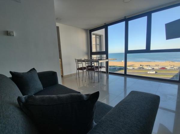 sala de estar con sofá y mesa con vistas en Frente al mar charlone en Mar del Plata