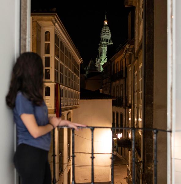 una mujer de pie frente a una ventana con un teléfono móvil en la Pension Santa Cruz de Santiago de Compostela