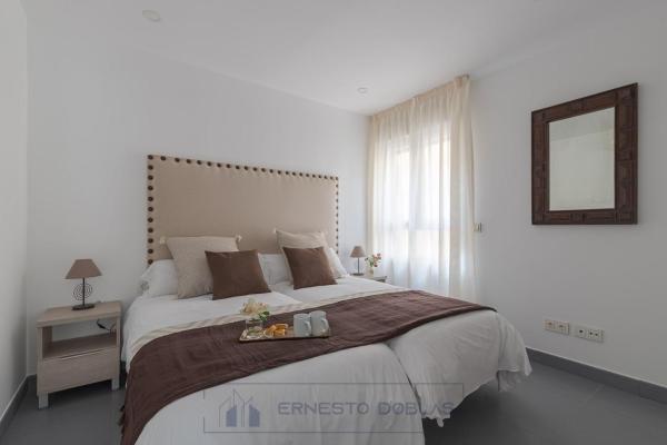 1 dormitorio blanco con 1 cama grande y espejo en Living4Malaga Juan de Austria, en Málaga