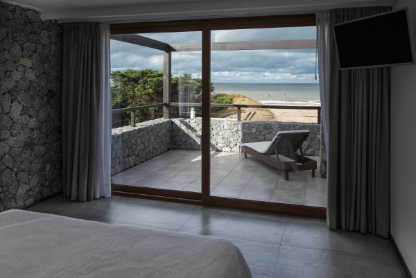 1 dormitorio con balcón con vistas a la playa en Rincon del Duende Resort y Spa de Mar en Mar de las Pampas