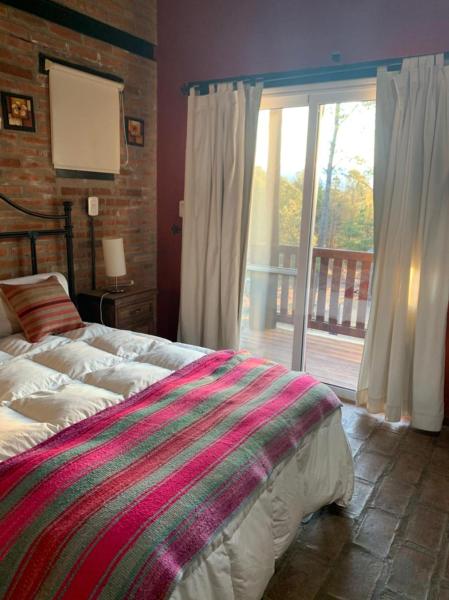 1 dormitorio con 1 cama y puerta corredera de cristal en Monte Barranco, en Villa Yacanto