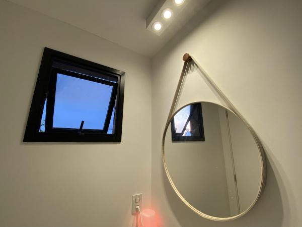baño con espejo redondo y ventana en 85 New studio w balcony, fast wifi and movie screen!, en São Paulo