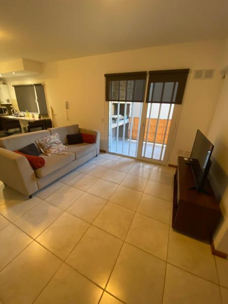 sala de estar con sofá blanco y TV en EDIFICIO CORAL 2 Dormitorio Y EDIFICIO ARENAS 1 Dormitorio en Puerto Madryn