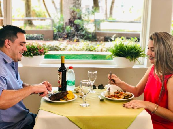 un hombre y una mujer sentados en una mesa comiendo comida en Gran Hotel Tourbillon & Lodge en Puerto Iguazú