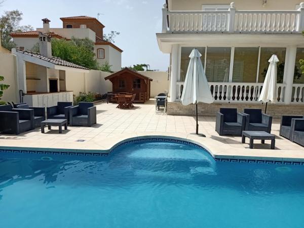 una piscina con sillas y sombrillas junto a una casa en Villa de lujo en Torremolinos, en Torremolinos