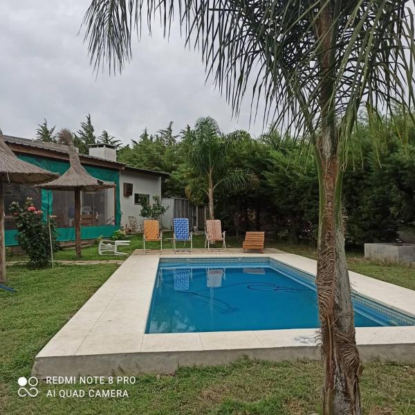 una piscina con una palmera al lado de una casa en Cabañas :Doña María Nuñez en Gualeguaychú