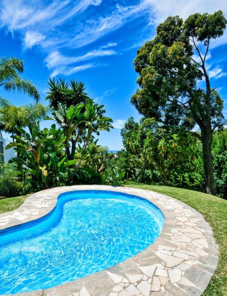 una piscina con agua azul y árboles en el fondo en Stay in Paradise Luxury Apartment, en Marbella
