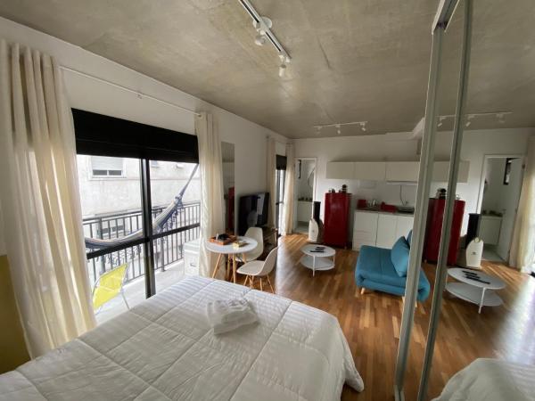 1 dormitorio con cama blanca y balcón en 85 New studio w balcony, fast wifi and movie screen!, en São Paulo