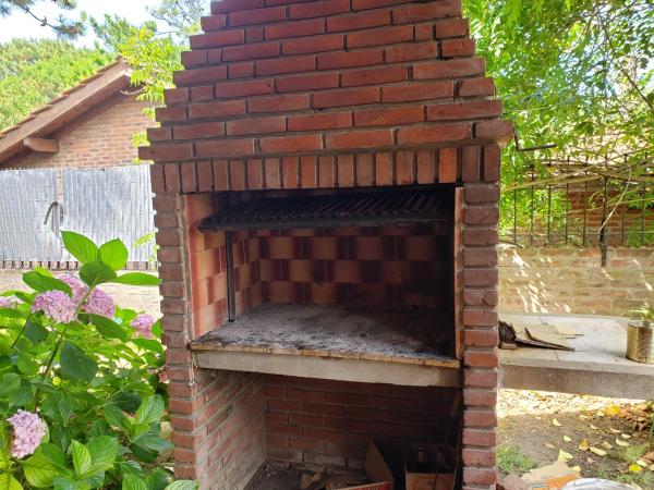 un horno de pizza de ladrillo al aire libre en un jardín en la Casa Tinta Roja 1 de Villa Gesell