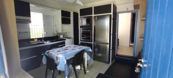 cocina con mesa y refrigerador de acero inoxidable en NaPraia Mariscal, en Bombinhas