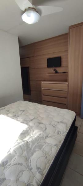 1 dormitorio con 1 cama y pared de madera en NaPraia Mariscal, en Bombinhas
