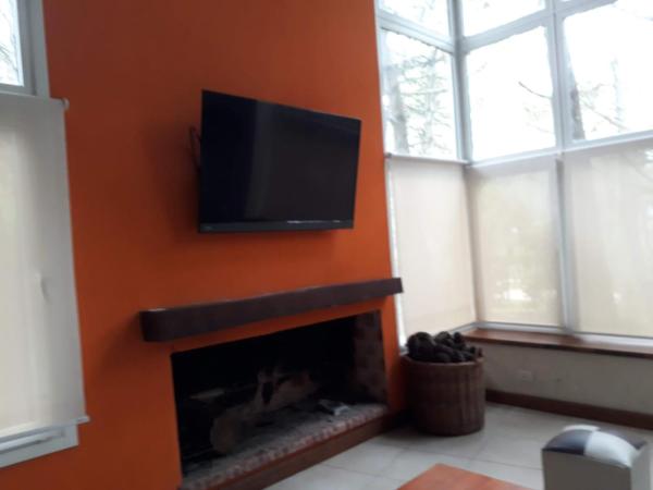sala de estar con chimenea y TV de pantalla plana en la pared en La Eulogia - Mar de las Pampas en Mar de las Pampas