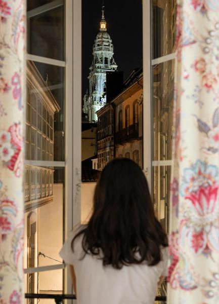 una mujer de pie frente a una ventana mirando a la Pension Santa Cruz de Santiago de Compostela