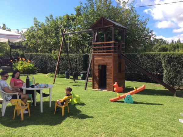 una familia sentada en un patio trasero con una casa de juegos en Complejo Turístico Las Catalpas, en Mina Clavero