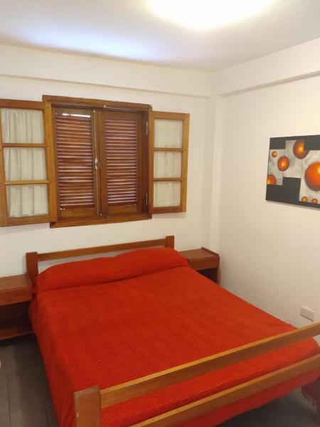 1 dormitorio con 1 cama con colcha roja en Departamentos Centro, en Mina Clavero