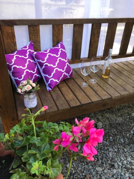 two pillows and two glasses on a bench with flowers at Charmoso apto com clima de casa em Canasvieiras in Florianópolis