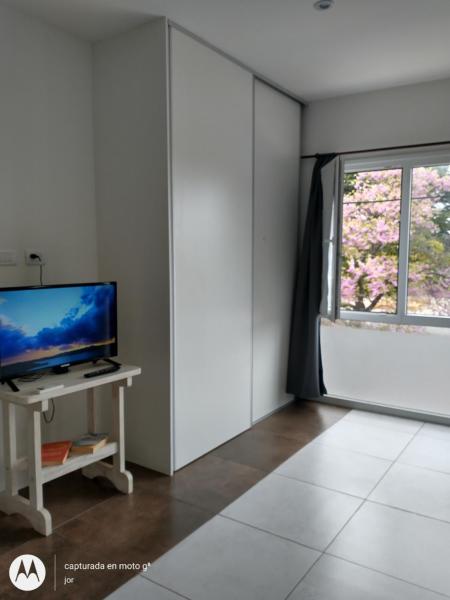 sala de estar con TV y ventana en Departamento Serrano en Tandil
