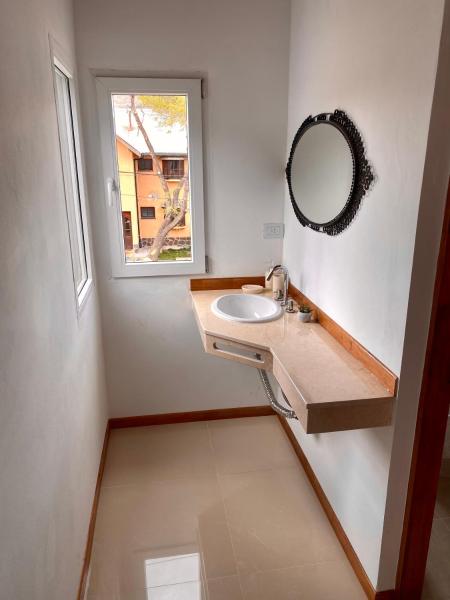 baño con lavabo, espejo y ventana en Terrazas de la Patagonia en Esquel