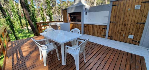 una mesa blanca y sillas en una terraza de madera en EL PINAR CASA DE PLAYA en Balneario Mar Azul