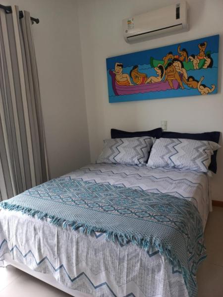 1 cama en un dormitorio con una pintura en la pared en Viapiana Cobertura 301, en Bombinhas