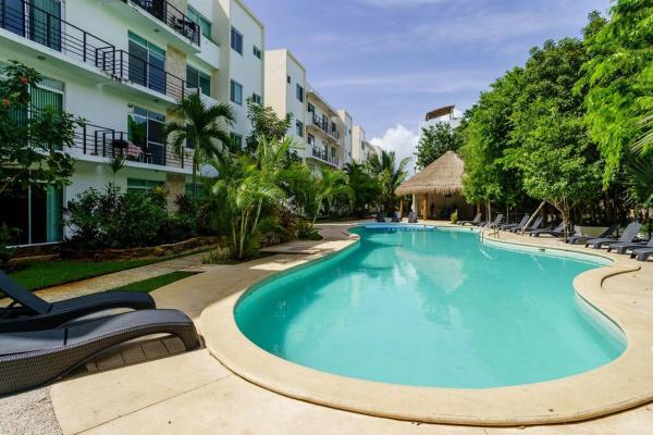 una piscina en un complejo con sillas y un edificio en Punta Estrella By Abna, en Playa del Carmen