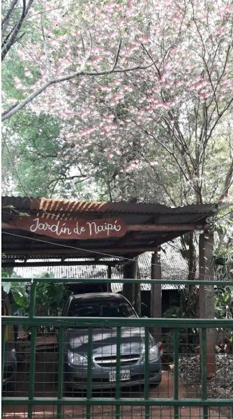un coche aparcado bajo un dosel con flores rosas en Jardín de Naipí 3 en Puerto Iguazú