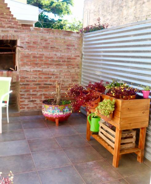 un patio con plantas, una mesa y una pared de ladrillo en Casita Playa Grande no grupos en Mar del Plata