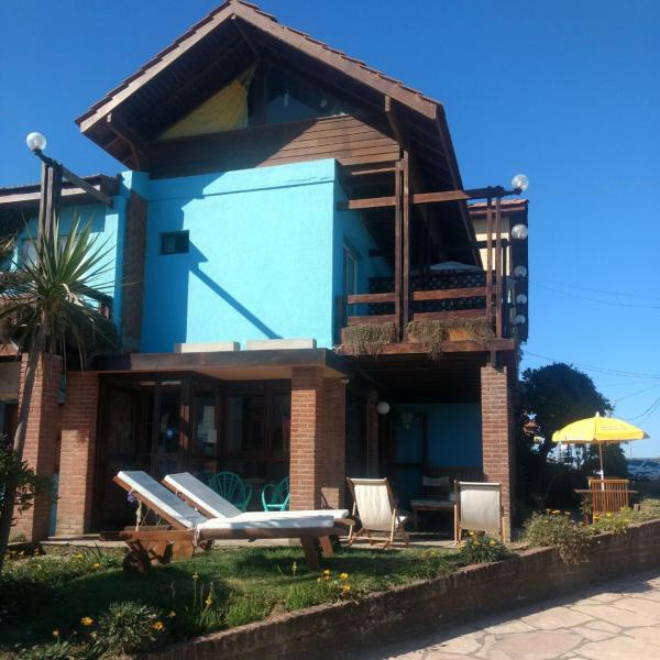 una casa azul con sillas y un paraguas en el Hotel Barracuda de Villa Gesell