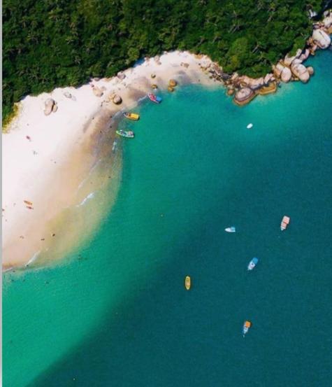 an aerial view of a beach with people in the water at Olhar da Barra Hospedagem - Refugio Urbano I in Florianópolis
