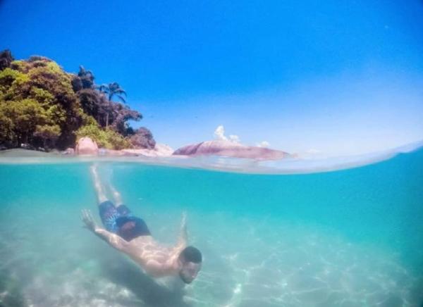 a man swimming in the water near an island at Olhar da Barra Hospedagem - Refugio Urbano I in Florianópolis