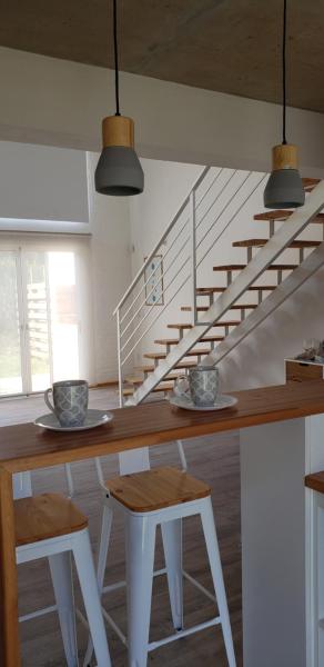 a dining table with two stools and a staircase at RANTALOMA Lofts in Piriápolis