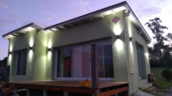 una pequeña casa verde con terraza de madera en La paz en Tandil