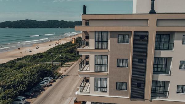 un edificio de apartamentos con una playa de fondo en HY Apart Hotel, en Bombinhas