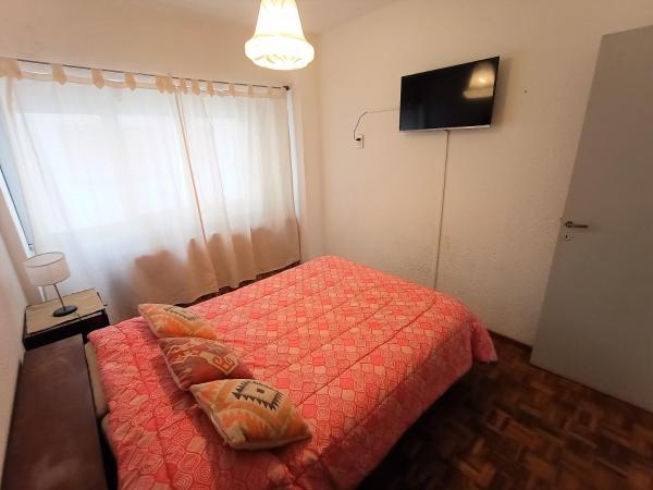 1 dormitorio con 1 cama con edredón rojo y TV en EF Departamentos Centro con Cochera en Mar del Plata
