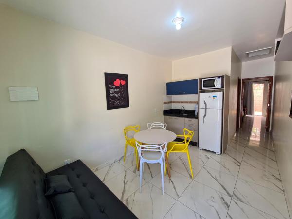 sala de estar con mesa, sillas y refrigerador en Miragem de Bombinhas DUO, en Bombinhas