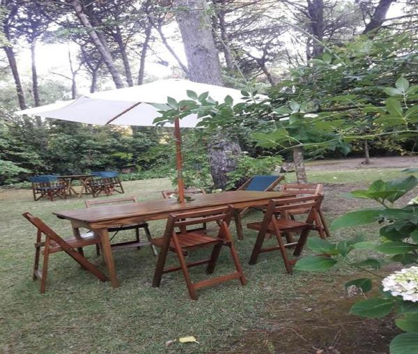 una mesa de picnic de madera con sombrilla y bancos en La Loma en Cariló