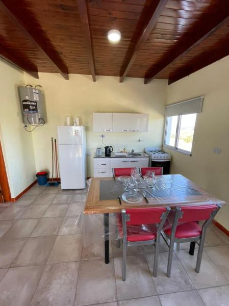 cocina con mesa, sillas y refrigerador en Cabañas PAIGÜEN, en Villa Yacanto