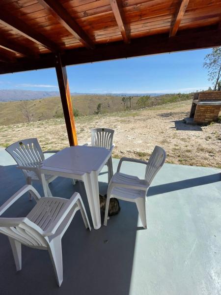 una mesa blanca y sillas en un porche con vistas en Cabañas PAIGÜEN, en Villa Yacanto