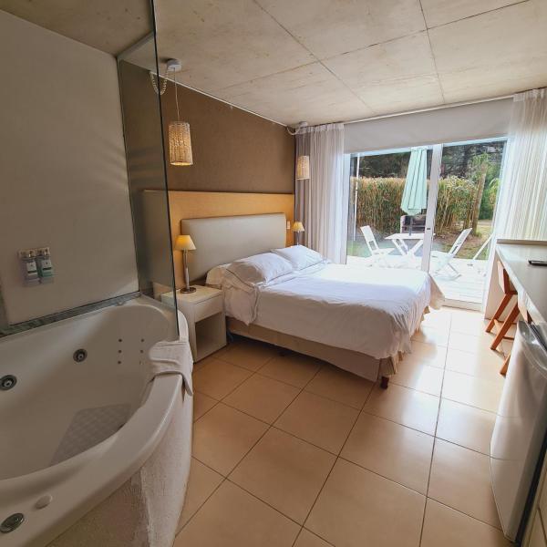 1 dormitorio con 1 cama y bañera junto a un baño en Villa Agostina Apart & Spa en Mar de las Pampas