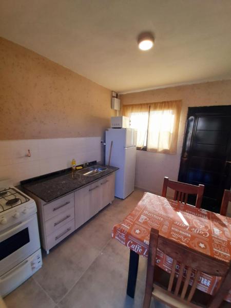 cocina con mesa y refrigerador blanca en SIMION en Villa Carlos Paz