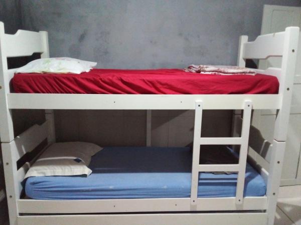a white bunk bed with a red mattress and a ladder at Casa a uma quadra da praia da Armação in Florianópolis
