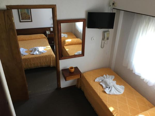 Habitación pequeña con 2 camas y espejo.  en Hostería Santa Bárbara en Villa Gesell